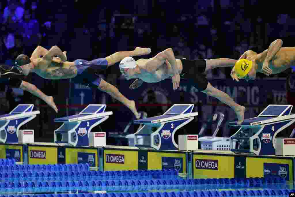 Drew Kibler, left, Patrick Callan, center, and Andrew Seliskar, right, dive at the start of a men&#39;s 100-meter freestyle semifinal during wave 2 of the U.S. Olympic Swim Trials, June 14, 2021, in Omaha, Nebraska.