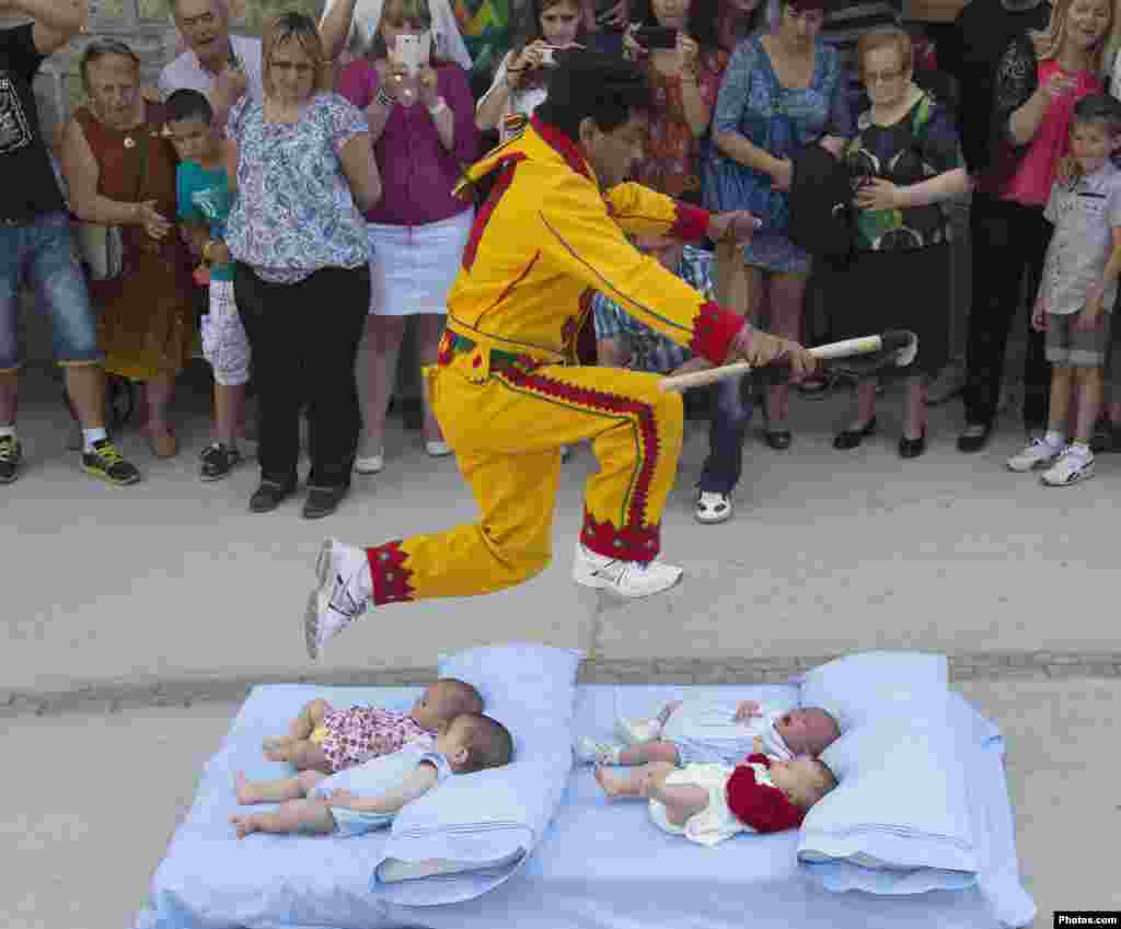 A man dressed in a red and yellow costume representing the devil, known as El Colacho, jumps over babies placed on a mattress during traditional Corpus Christi celebrations in Castrillo de Murcia, near Burgos, northern Spain.