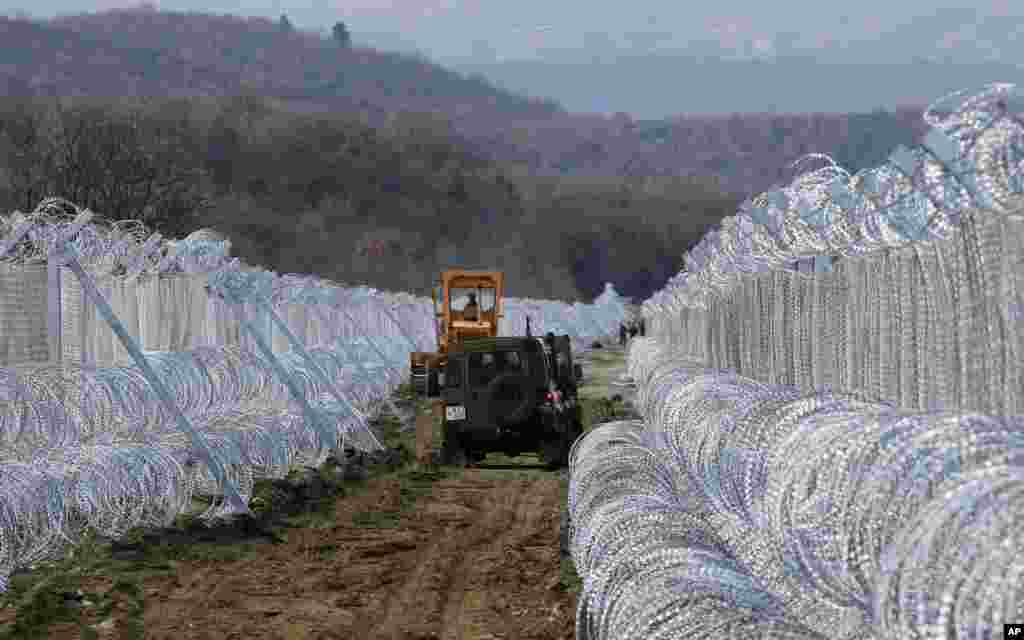 Macedonian Army vehicles move along a path between two lines of fence reinforced with razor wire, on the border line with Greece near the southern Macedonia&#39;s town of Gevgelija.