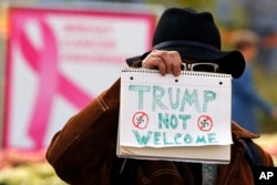 A man holds a sign outside the University of Pittsburgh's Presbyterian Hospital before the arrival of President Donald Trump's motorcade in Pittsburgh, Oct. 30, 2018.