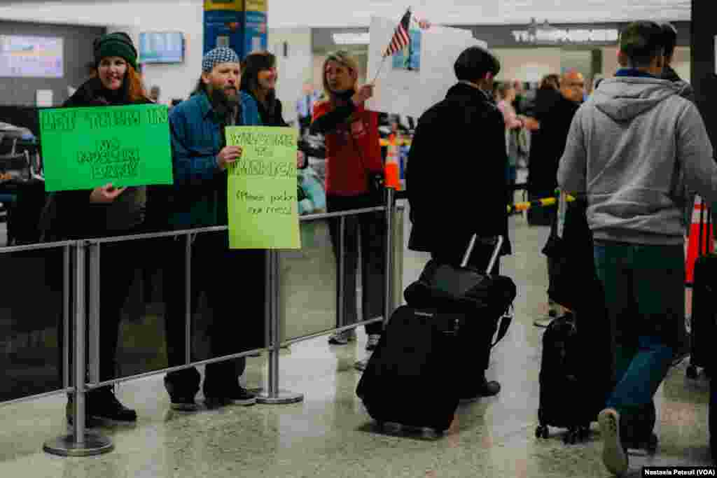Des manifestants accueillent les touristes et les résidents à l'aéroport international de Washington DC, le 31 janvier 2017. (VOA/Nastasia Peteuil)