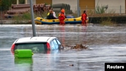 Rescue workers pulling a boat along, wade on a flooded street at San Gavino Monreale in Sardina island Nov. 18, 2013.