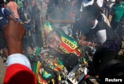 Supporters of the opposition Movement for Democratic Change party (MDC) of Nelson Chamisa burn an election banner with the face of Zimbabwe's President Emmerson Mnangagwa in Harare, Zimbabwe, Aug. 1, 2018.