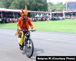 Menhukham, Yasonna Laoly, yang mengenakan pakaian tradisional Nias nampak mencoba mengendarai sepeda hadiah dari Presiden Joko Widodo (Courtesy: Setpres RI)