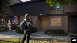 A passerby takes a picture of the townhouse rented by the San Bernardino attackers Syed Farook and his wife, Tashfeen Malik, Dec. 8, 2015, in Redlands, California.