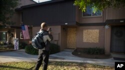 Un passant prenant avec son smartphone des photos de la maison louée par les terroristes de San Bernardino, Syed Farook et sa femme Tashfeen Malik, le 8 décembre 2015. (AP Photo/Jae C. Hong)