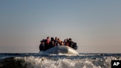 FILE - Refugees and migrants approach the Greek island of Lesbos on a dinghy after crossing the Aegean sea from the Turkish coast, on Monday, Dec. 7, 2015. 