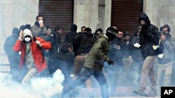 Protesters try to avoid a tear gas canister during clashes in central Athens, February 23, 2011