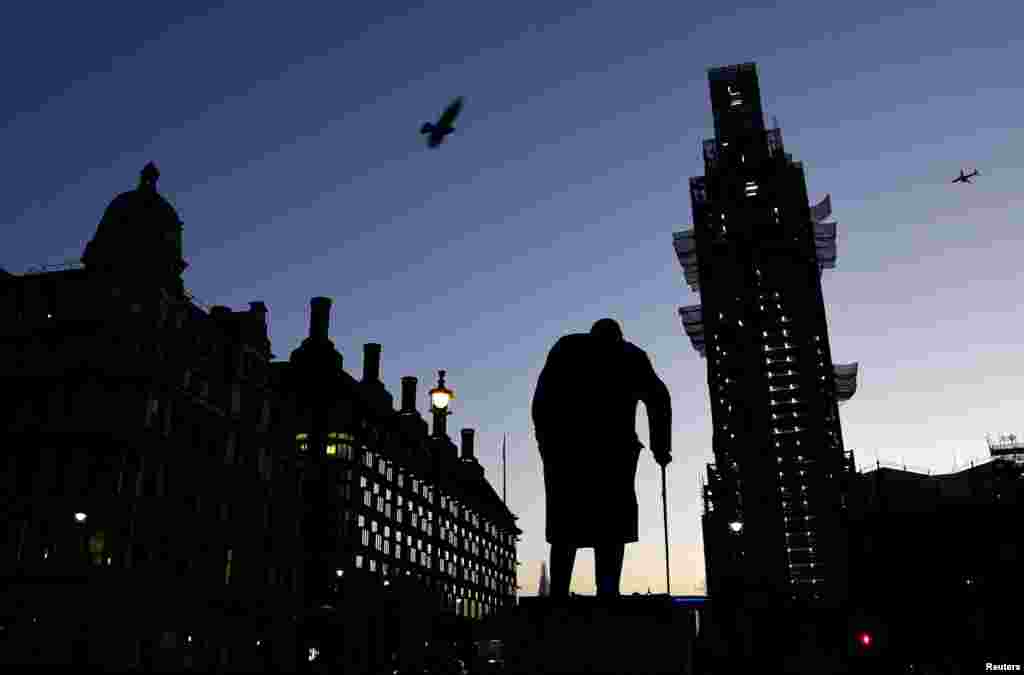 The sun comes up, silhouetting the statue of Winston Churchill and Big Ben, in the Westminster area of London.