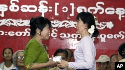 Burma's pro-democracy leader Aung San Suu Kyi (R) presents an Unknown Hero Award to a relative of Than Naing Oo, who is currently in prison, at National league for Democracy (NLD) head office in Yangon, April 17, 2011