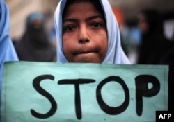 FILE - A Shiiite student holds a placard during a protest against an attack by Taliban militants at an army-run school in Peshawar the previous day, in Karachi, Dec. 17, 2014.