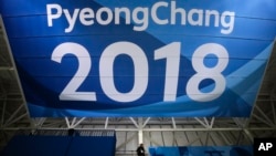 FILE - In this Feb. 6, 2018 file photo, a photographer walks down the steps underneath a large banner at the Gangneung Hockey Center ahead of the 2018 Winter Olympics in Gangneung, South Korea. 