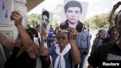 Relatives of war victims protest against Carlos Vides, a former Salvadoran minister of defense, upon his arrival at San Salvador's Oscar Romero airport, April 8, 2015. 