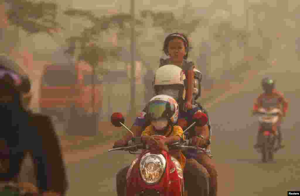 A family rides on a motorcycle in the haze which hit Duri on Indonesia's Riau province. Indonesian police arrested two farmers for illegally starting fires to clear land in Sumatra - the first detentions linked to blazes that have blanketed neighboring Singapore and Malaysia with thick smog for days.