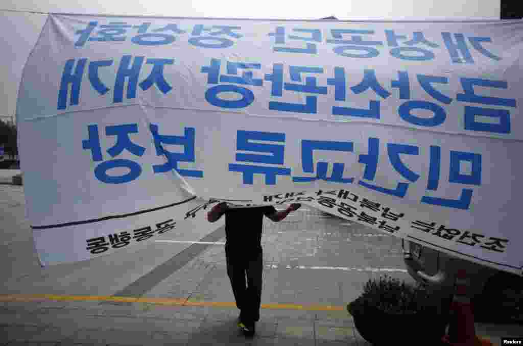 A protester adjusts a giant banner, during a rally demanding the resumption of the inter-Korean dialogue, against the government in front of the Integrated Government Complex in Seoul. The banner reads "Normalization of the Kaesong Industrial Complex (KIC), resumption of the Mt. Geumgang tours, Guarantee of non-governmental interaction"