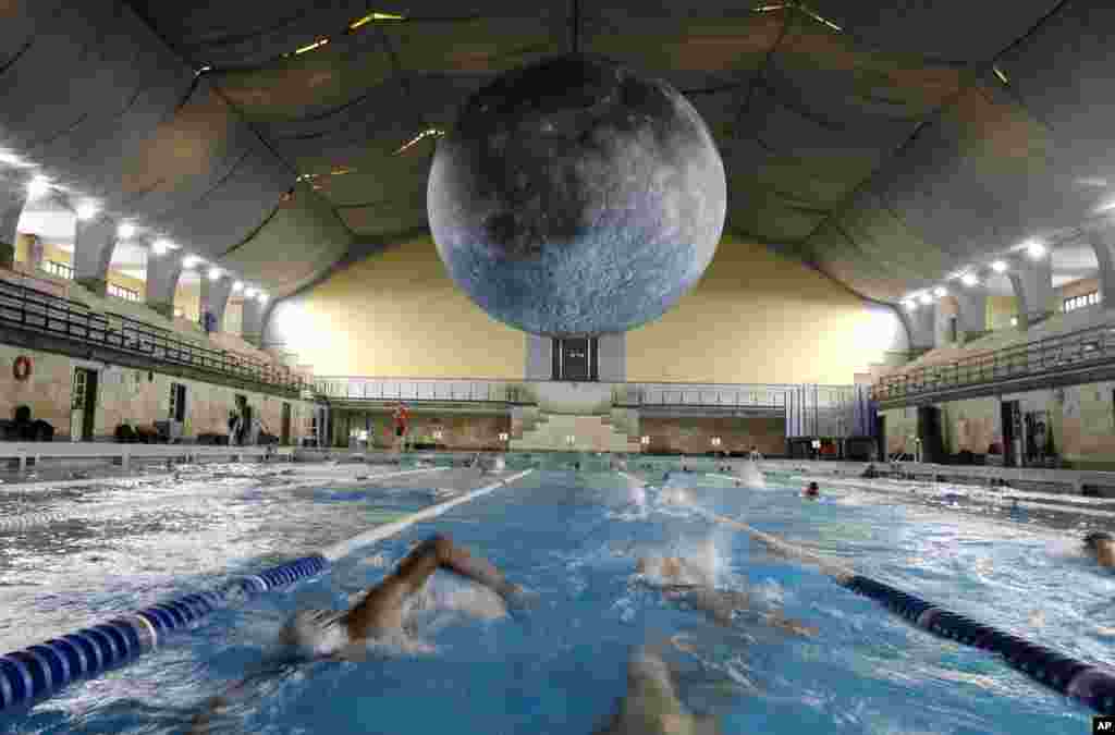 در یک استخر در میلان ایتالیا، اثر هنری لاک جرامشچ، هنرمند بریتانیایی که یک سازه بزرگ به شکل کره ماه است، آویزان شده است.