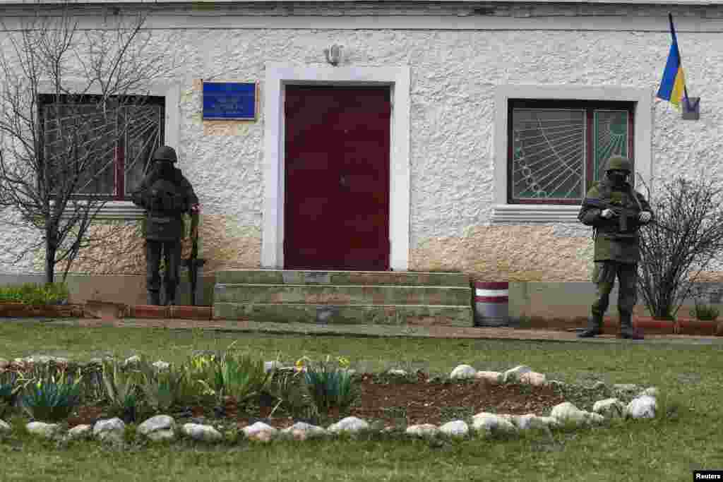 Armed men, believed to be Russian servicemen, stand guard outside an entry to a Ukrainian military base in the village of Perevalnoye near the Crimean city of Simferopol, March 9, 2014.&nbsp;