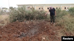 A member of the February 17th Brigade, points at the site of a bombing at the brigade's base after it was bombed by two jets in Benghazi, Libya, May 28, 2014. 