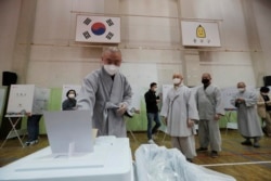 A Buddhist monk wearing a face mask to help protect against the spread of the new coronavirus casts his early vote for the upcoming parliamentary election at a polling station in Seoul, South Korea, Friday, April 10, 2020.