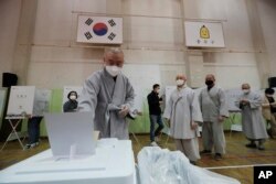 A Buddhist monk wearing a face mask to help protect against the spread of the new coronavirus casts his early vote for the upcoming parliamentary election at a polling station in Seoul, South Korea, Friday, April 10, 2020.