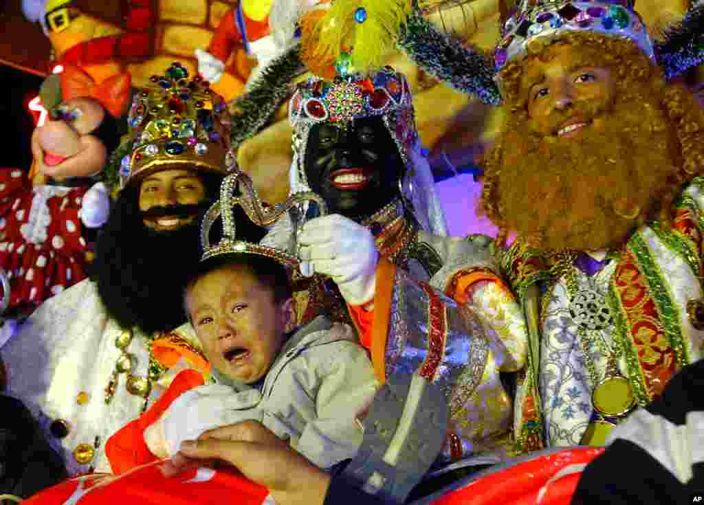 Estos tres reyes magos mexicanos, Raúl, José y Ernesto, posan para una foto con un bebé llorando en Ciudad de México, durante la celebración de la Epifanía, una fiesta cristiana en la que los pequeños reciben regalos en México y otros países.