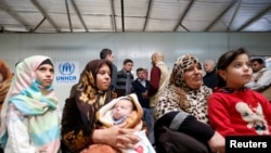 FILE - Syrian refugees wait to receive treatment at a health center, during the visit of Slovenian President Borut Pahor (back C) to the refugee camp Al-Zaatari in Jordan, near the border with Syria, Dec. 3, 2016.