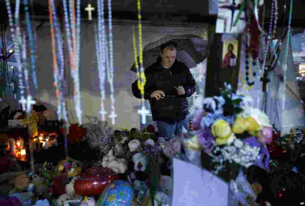 Ben Toby of Sandy Hook visits a memorial to the Newtown shooting victims during a heavy rain in the Sandy Hook village of Newtown, Connecticut, December 21, 2012. 