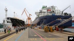 Workers walk past large-sized liquefied natural gas (LNG) carriers under construction at the Daewoo Shipbuilding and Marine Engineering facility in Geoje Island, South Korea, Dec. 7, 2018. 