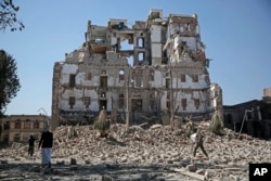 FILE - Houthi Shi'ite rebels walk amid the rubble of the Republican Palace that was destroyed by Saudi-led airstrikes, in Sana'a, Yemen, Dec. 6, 2017.