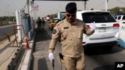 An Iraqi federal policeman uses a device meant to detect bombs at a checkpoint in Baghdad, Iraq, Oct. 11, 2014. 