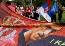 Anggota komunitas Serbia setempat memegang bendera dan spanduk di luar pusat penahanan pemerintah tempat juara tenis Serbia Novak Djokovic tinggal di Melbourne, Australia, pada 8 Januari 2022. (Foto: AFP)