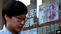 A pedestrian passes by a bank window panel displaying the latest renminbi banknote in Beijing, Feb. 27, 2017. China has raised interest rates on short-term loans for the third time.