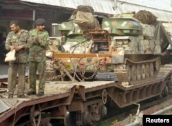 Indian soldiers stand in front of a tank being transported on a railcar at a station in Ambala, Dec. 30, 2001. India and Pakistan massed troops along their borders in the biggest such buildup in 15 years following the Dec. 13 attack on the Indian Parliament.