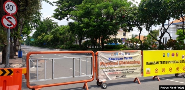 Jalan Raya Darmo di Surabaya ditutup untuk mengurangi mobilitas warga dan kendaraan di jalan itu, 4 April 2020. (Foto: Petrus Riski/VOA)