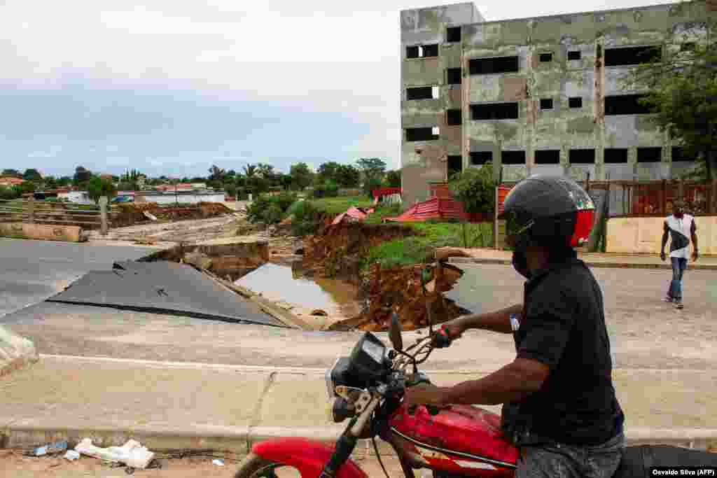 Um motociclista passa pela ponte Kamorteiro destru&#237;da, no Talatona, Luanda - Angola, a 20 de Abril depois das fortes chuvas de 19
