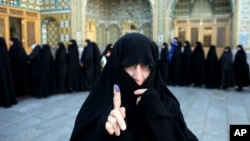 An Iranian woman displays her ink-stained finger after voting in the parliamentary and Experts Assembly elections at a polling station in Qom, Feb. 26, 2016.