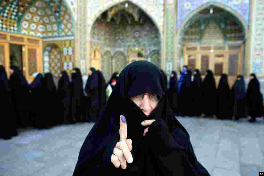 An Iranian woman displays her ink-stained finger after voting in the parliamentary and Experts Assembly elections at a polling station in Qom. Polls opened Friday in parliamentary elections, the country&#39;s first since its landmark nuclear deal with world powers last summer.