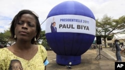 A supporter of Cameroon President Paul Biya stands next to a giant election campaign ball in Yaounde, Cameroon, October 8, 2011.
