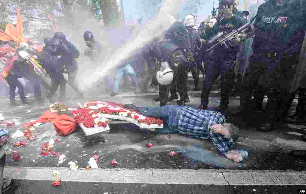 A man lies on the ground as Turkish police use a water cannon to disperse protestors during a May Day rally near Taksim Square in Istanbul.