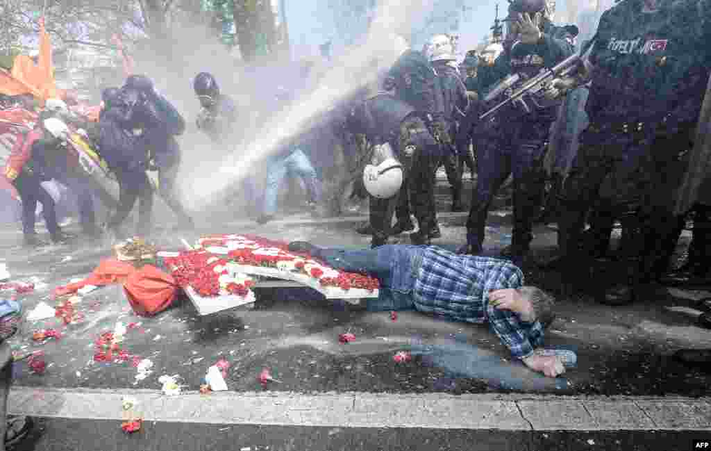 Seorang pria terbaring di tanah saat polisi Turki menggunakan meriam air untuk membubarkan demonstran dalam pawai Hari Buruh dekat Alun-Alun Taksim di Istanbul (1/5). ​(AFP/Bulent Kilic)