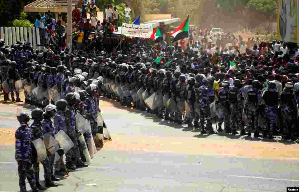 Riot police officers hold position against protesters near the Parliament buildings in Omdurman, Khartoum, Sudan.