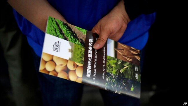 一位中国访客在上海国际大豆展上手握一家美国大豆公司的传单。2018年4月12日。