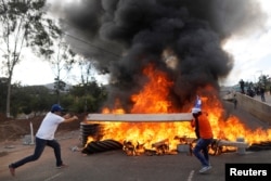 Demonstrators throw wood onto burning tires at a barricade during a protest as Honduran President Juan Orlando Hernandez is sworn in for a new term in Tegucigalpa, Honduras, Jan. 27, 2018.