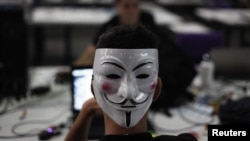A man wearing a Guy Fawkes mask surfs the web during a "Campus Party", an annual week-long, 24-hour technology festival that gathers around 8000 hackers, developers, gamers and computer geeks from around the world in Sao Paulo, January 30, 2013.