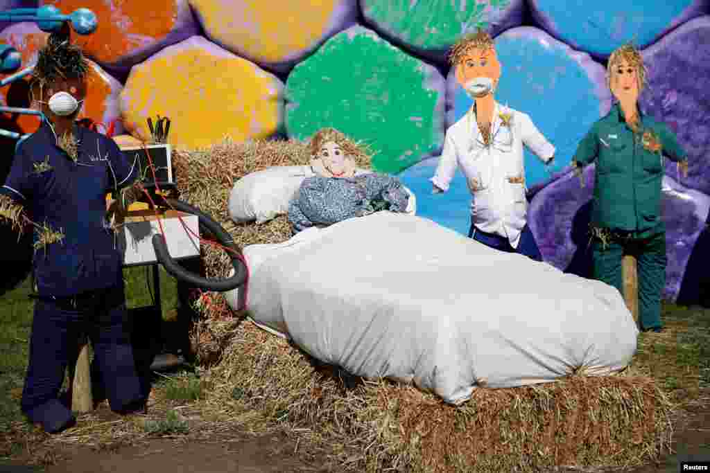 Scarecrows dressed as doctors and a patient are seen in front of rainbow colored hay bales on a farm in Billinge in Billinge, Britain.