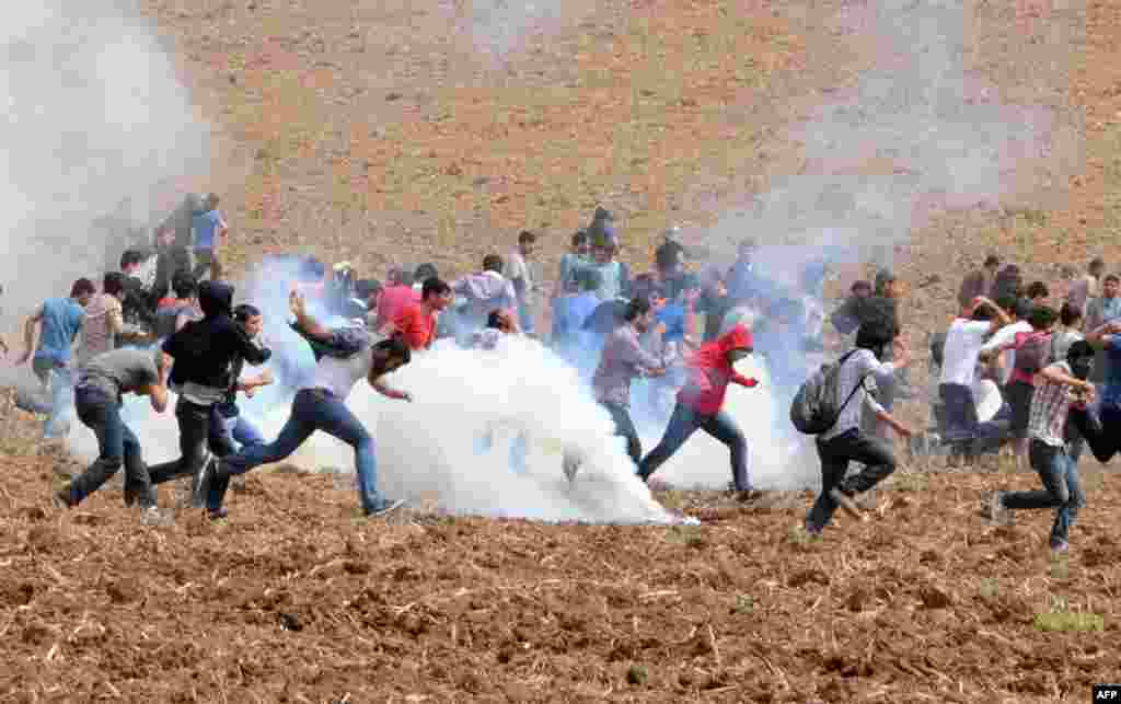 Protesters flee as tear gas explodes in a field during a demonstration near Dicle University, in Diyarbakir, Turkey. Leftist Kurdish students protest after clashes between left and right-wing groups inside the universtiy. 