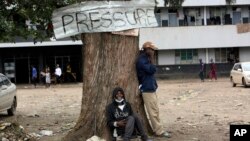 A man smiles while sitting under a tree in Harare, Zimbabwe, Thursday, Sept, 16, 2021. Zimbabwe has told all government employees to get vaccinated against COVID-19 or they will not be allowed to come to work. I