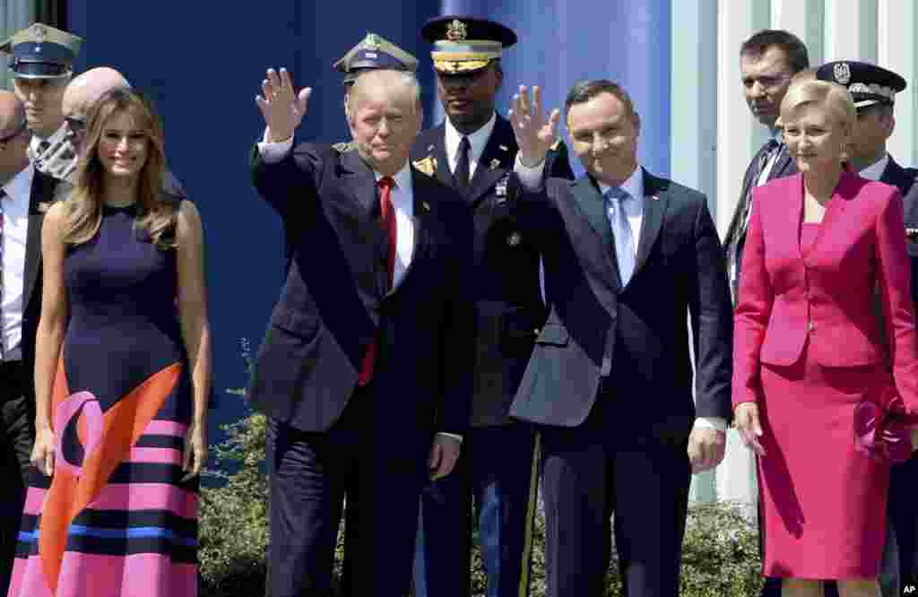 U.S. President Donald Trump, left, waves along with Poland&#39;s President Andrzej Duda, as U.S. First Lady Melania Trump, left and Poland&#39;s first lady Agata Kornhauser-Duda, right, stand by, in Krasinski Square, in Warsaw, July 6, 2017.