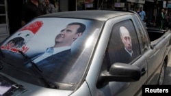 FILE - A poster of Syria's President Bashar al-Assad and a photo of Russian President Vladimir Putin, right, are seen on a car near Latakia, Syria, May 26, 2014.