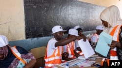 Un responsable de la Commission électorale de Zanzibar (ZEC) remet un bulletin de vote à l'école primaire Mtupepo de Daraja Bovu, Zanzibar, le 27 octobre 2020.